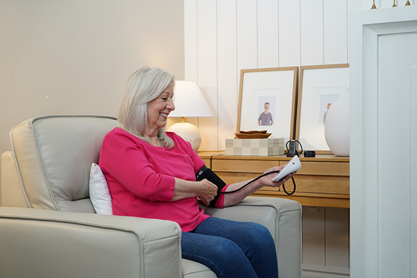 elderly woman sitting on couch at home checking blood pressure