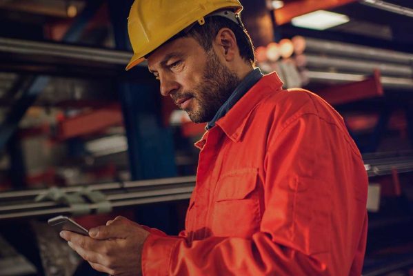 worker with yellow hardhat checking in on app